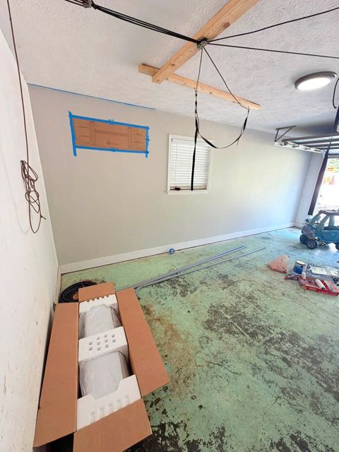 Garage wall marked out for a mini-split, with the new unit still in its box